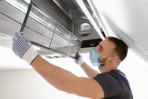 Male technician cleaning industrial air conditioner indoors