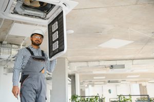 Professional technician maintaining modern air conditioner indoors. Space for text.