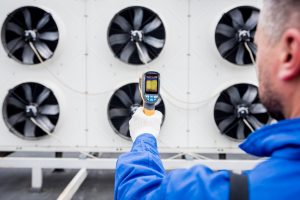 Technician uses a thermal imaging infrared thermometer to check the condensing unit heat exchanger